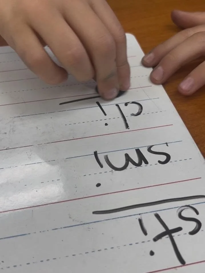 A clock drawn with white chalk on a black chalkboard, showing the time as 1:00.
