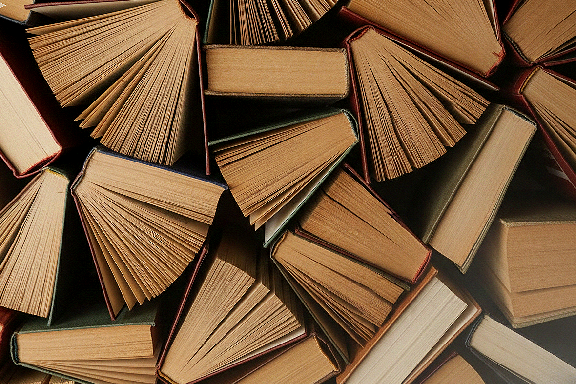 A collection of open books arranged with their pages fanned out, creating a pattern of overlapping pages.