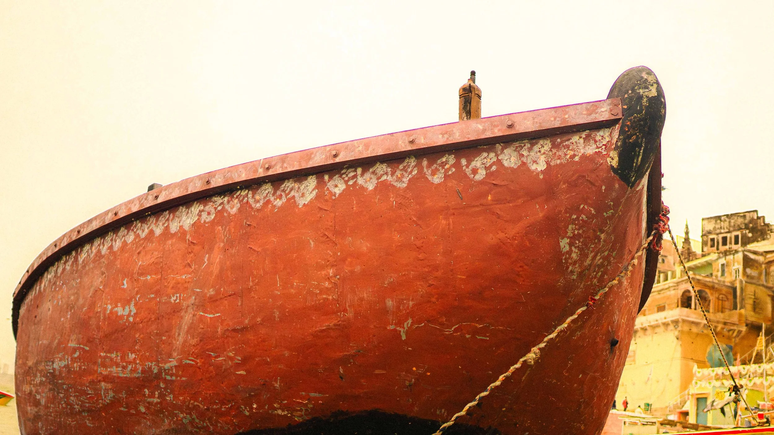 Close-up view of a large weathered red boat on the riverfront in Benares, India.