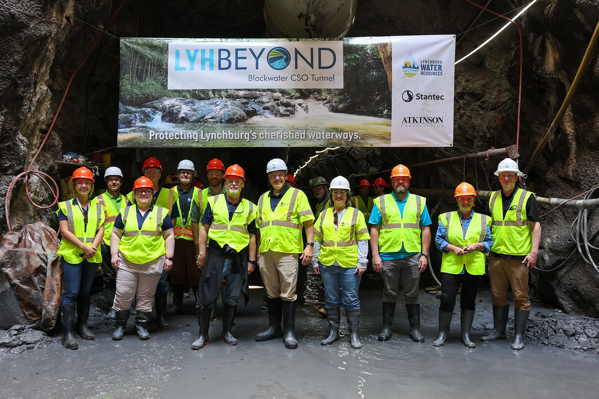 Tunnel Tour guests gather for a group photo under a project banner in the Blackwater CSO Tunnel.