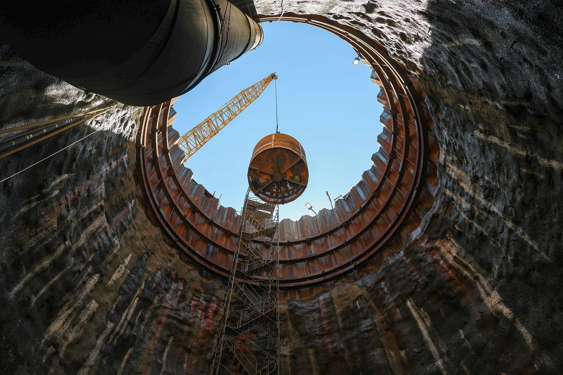 A crane lifts a construction cage filled with guests out of the tunnel shaft.