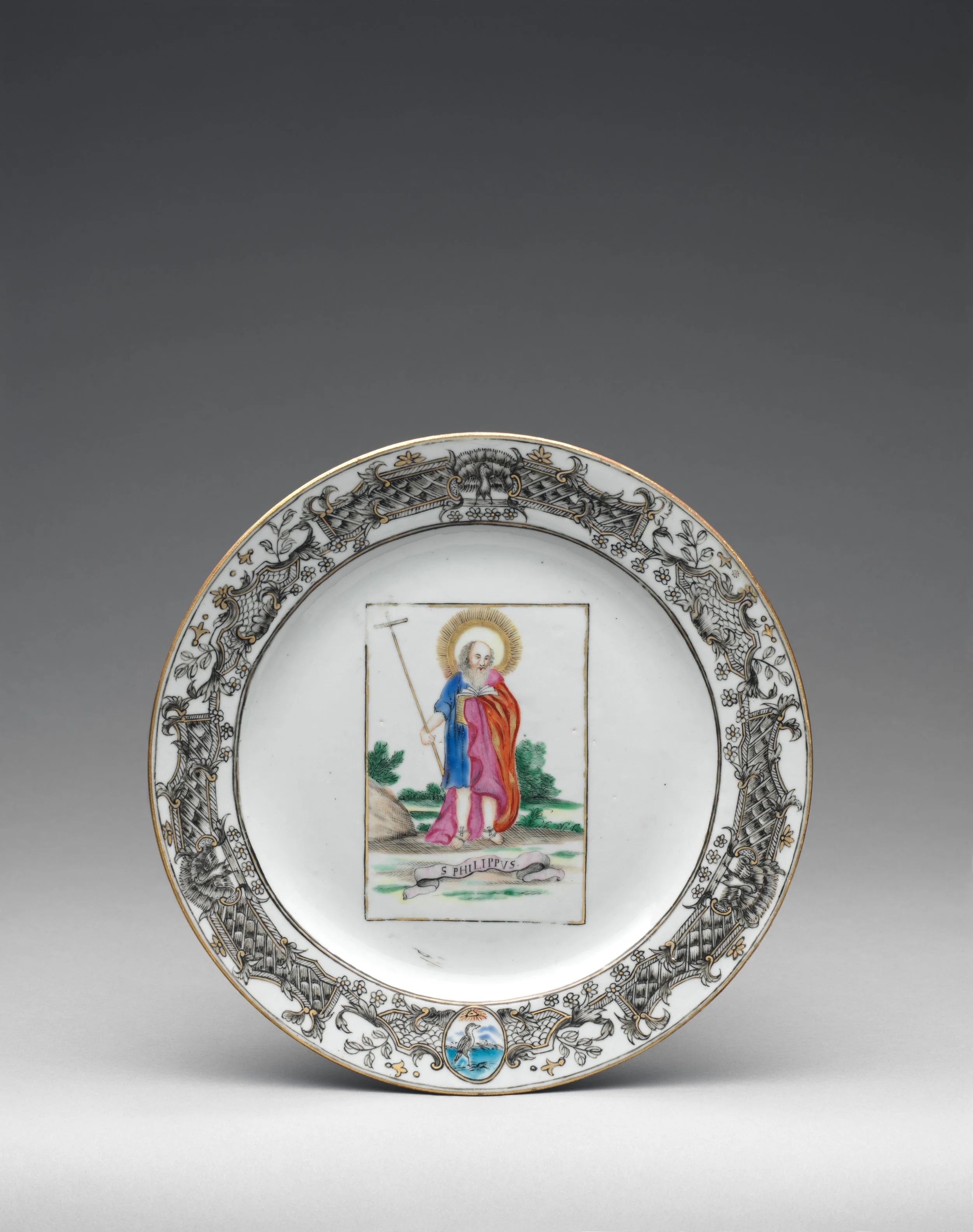 A decorative porcelain plate featuring a painted biblical scene of Jesus Christ, with ornate gold and black floral patterns around the rim, and a small scenic panel with a bird at the bottom.