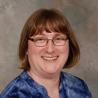 Smiling person with glasses and short hair