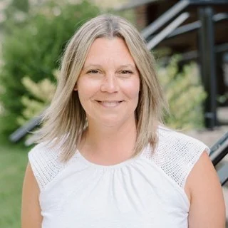 Woman smiling outdoors with greenery in background