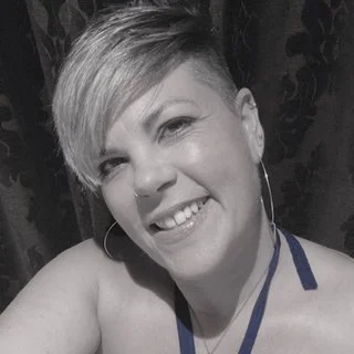 Person with short hair smiling and wearing hoop earrings.