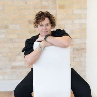 Person sitting on a chair backward against a brick wall