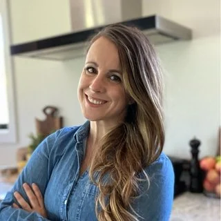 Smiling woman in a denim shirt standing in a kitchen