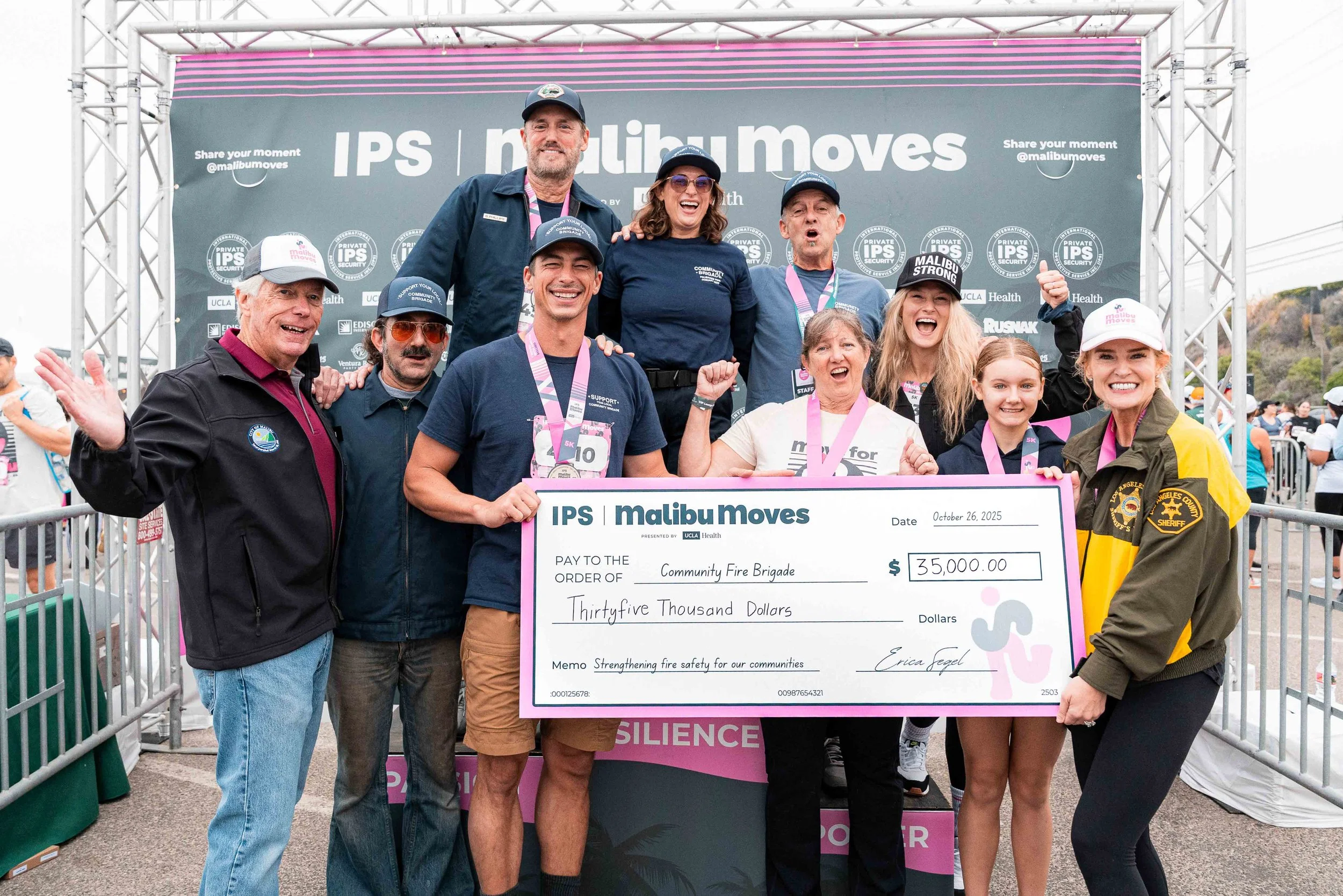 Group photo of Commander Seetoo, Malibu Mayor & Councilmembers and local community brigade responders holding a thirty-five thousand dollar donation check for the Community Fire Brigade.
