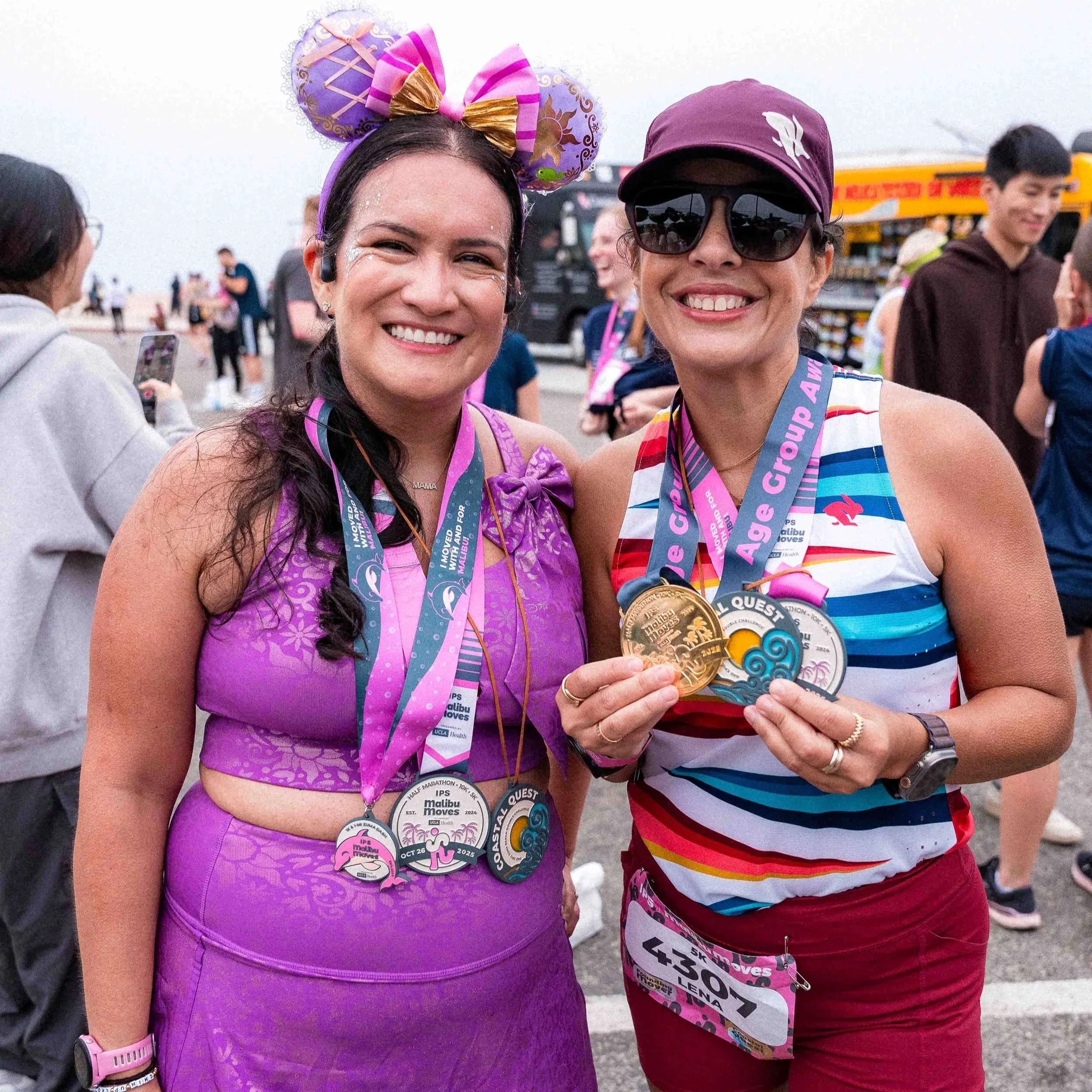 A Malibu Moves runner holding up three Coastal Quest medals