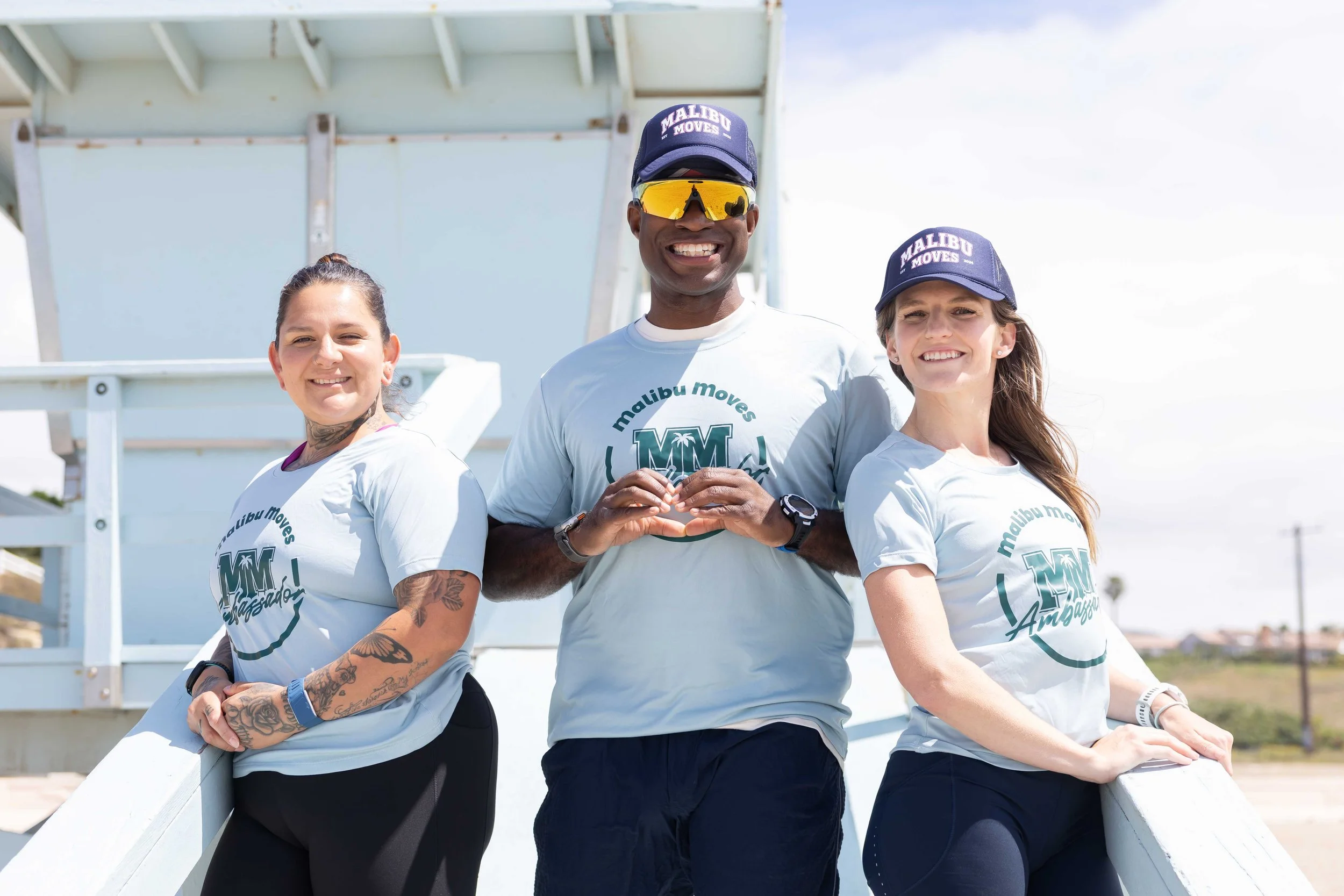2026 Malibu Moves Ambassadors Elizabeth, Moe and Dr. Jessica by one of the iconic lifeguard towers at Zuma Beach, Malibu.