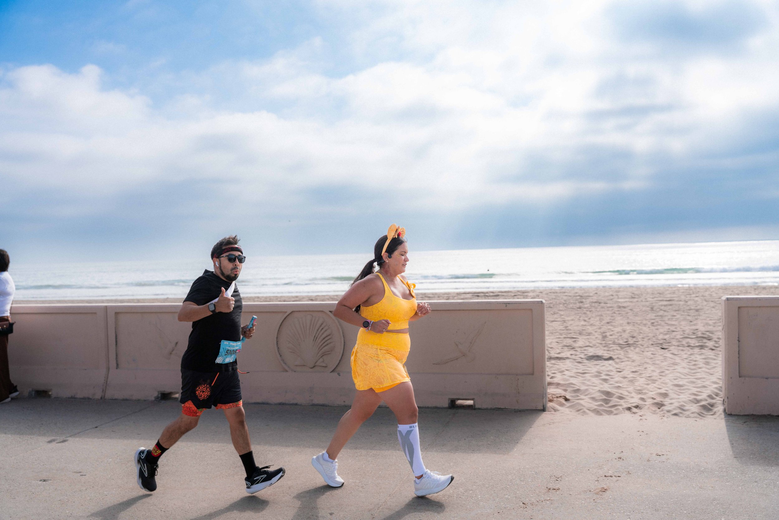 1-Mi Zuma Dash participants running on the Zuma Beach bike path with the Pacific ocean as their background.