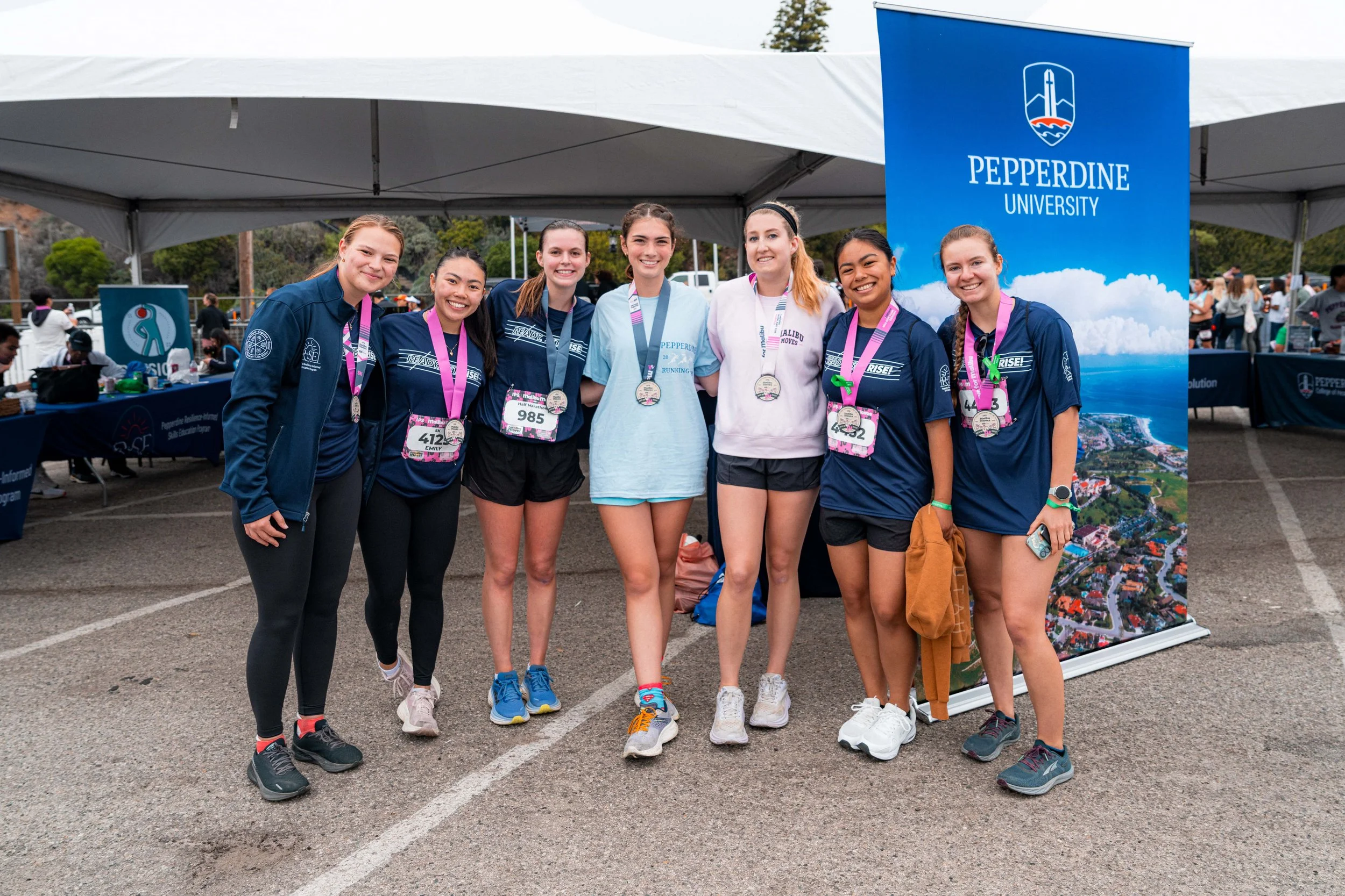 Pepperdine University students wearing finisher medals pose together at the Malibu Moves event, celebrating movement, community, and student well-being.