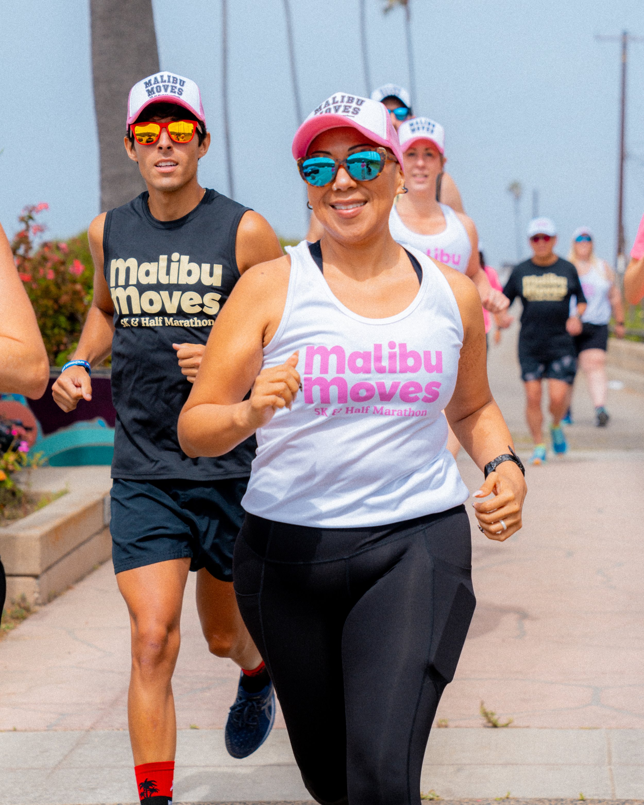 Malibu Moves Ambassadors Jen and Mark running by the Zuma Beach sign wearing the official ambassadors' swag.
