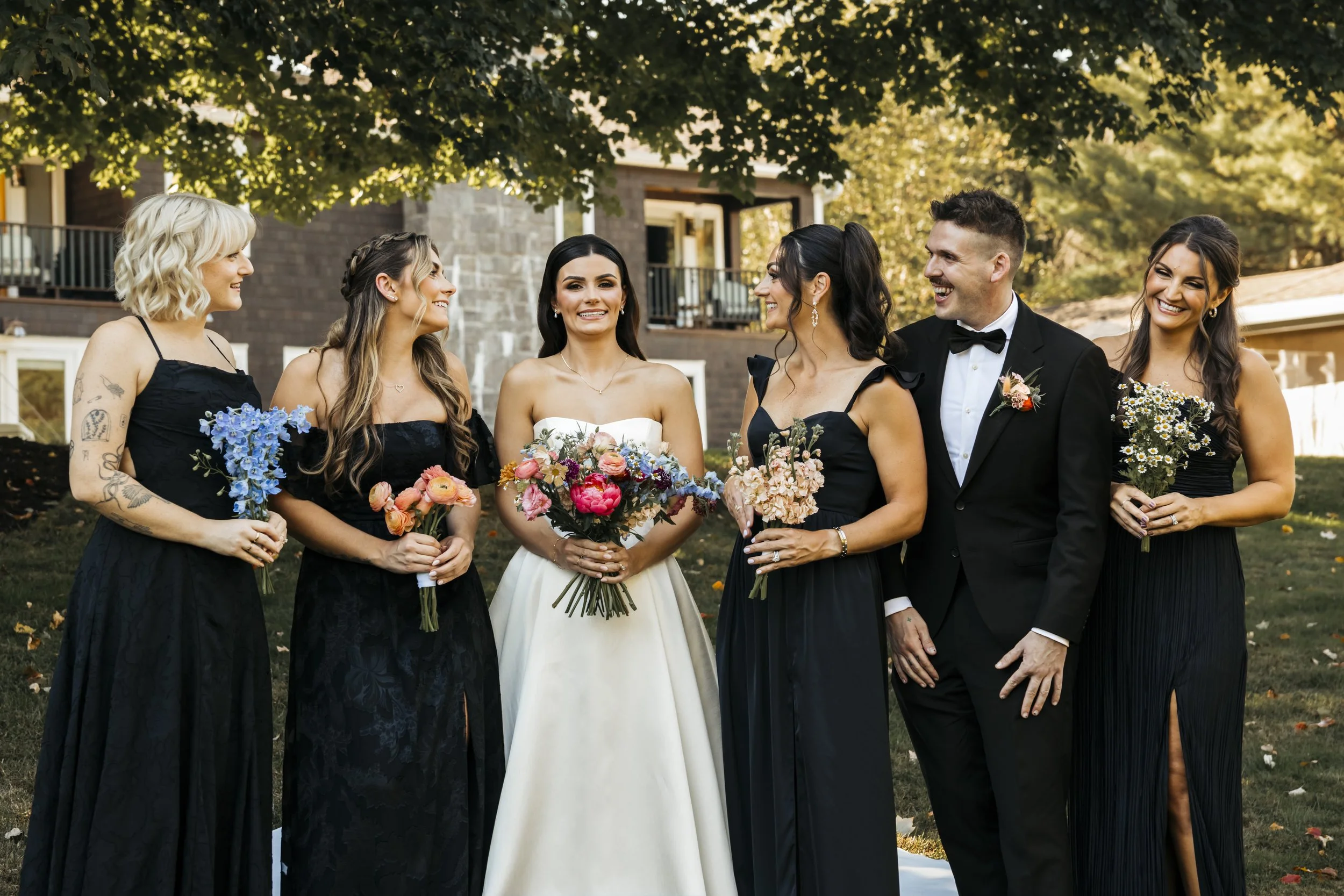 Group of bridesmaids and a groom standing outdoors at a wedding.