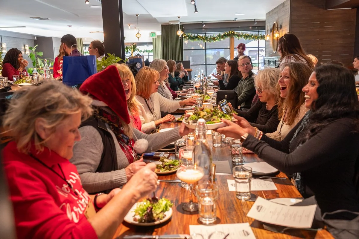 People gathered around a long dining table. they are laughing and enjoying conversation.
