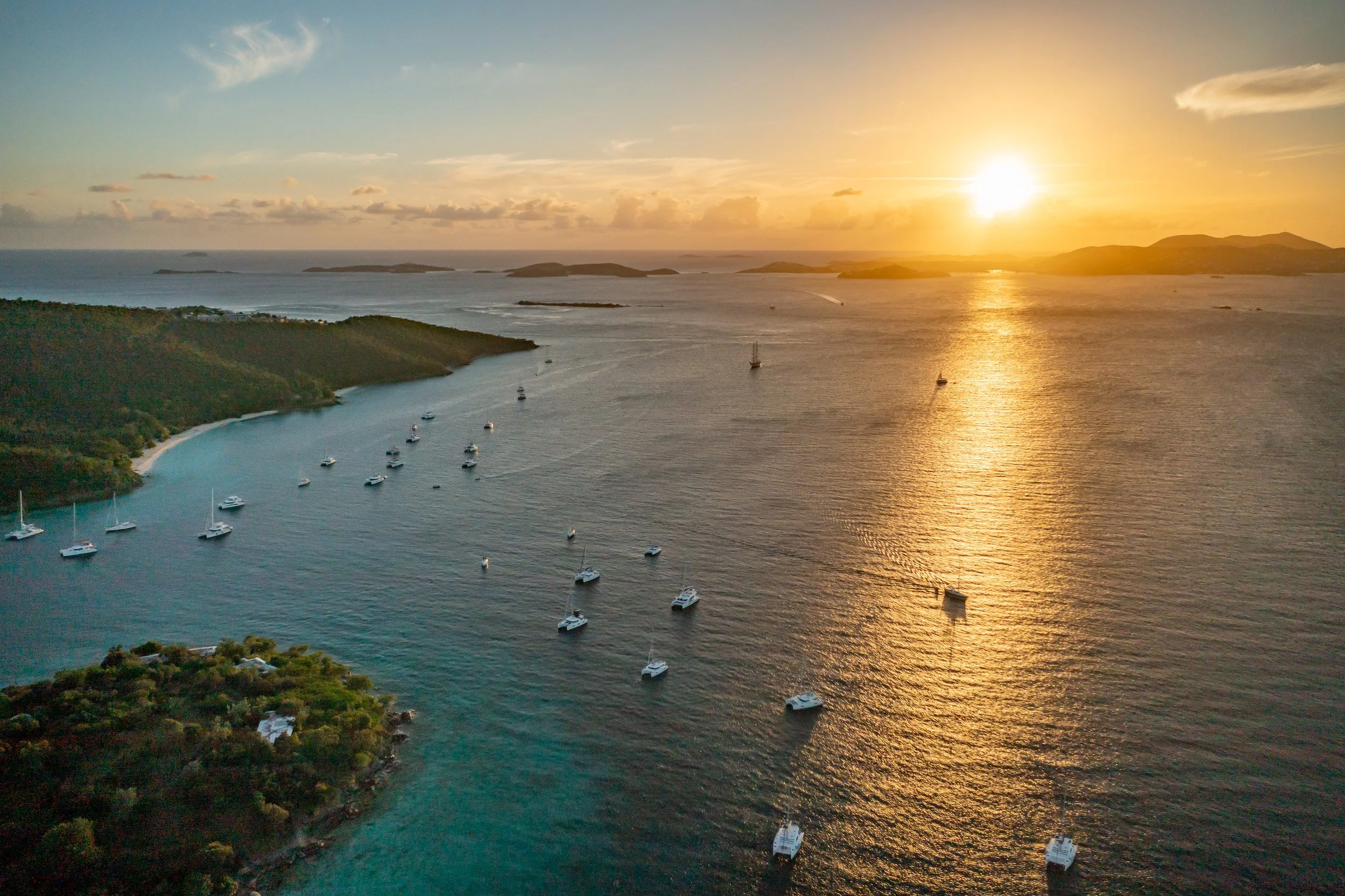 Sunset over tropical Carribean waters with sailboats in the bay.