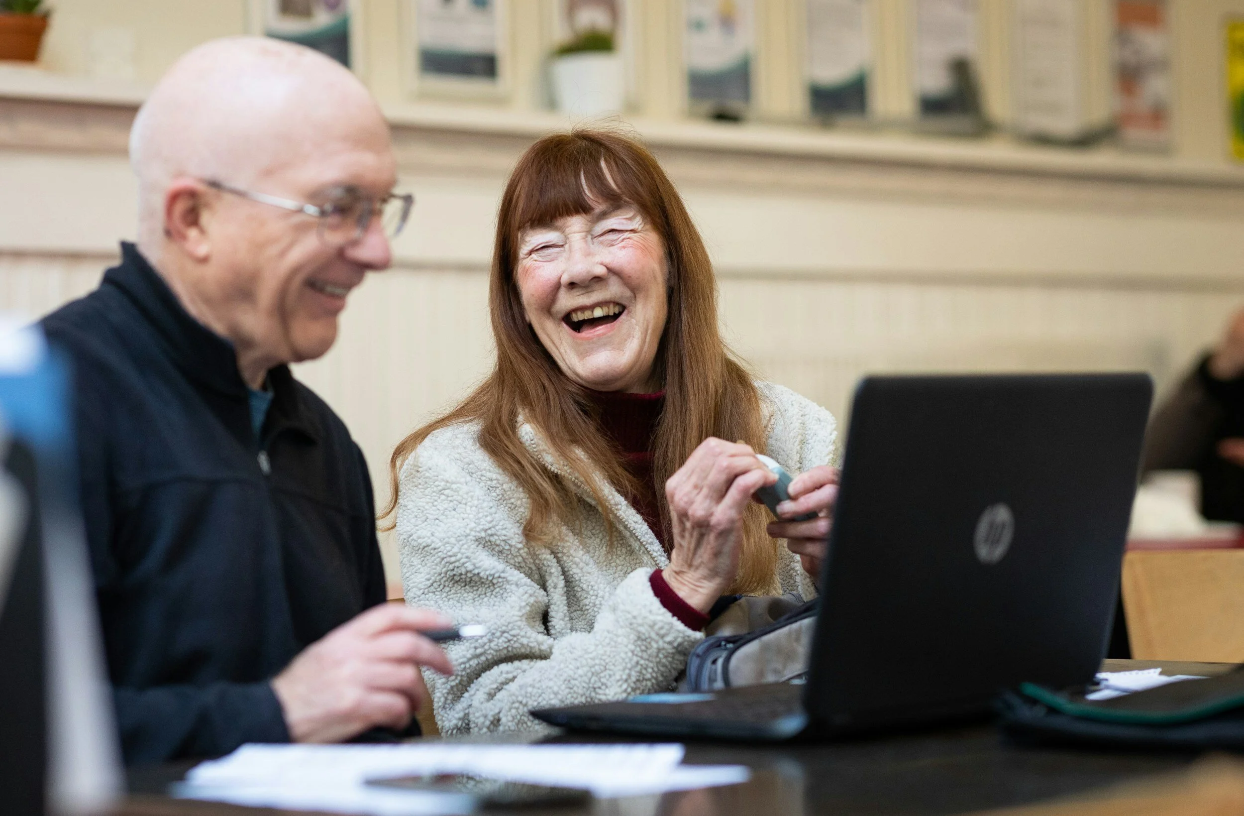 a man looking at a computer and a woman looking at him and smiling