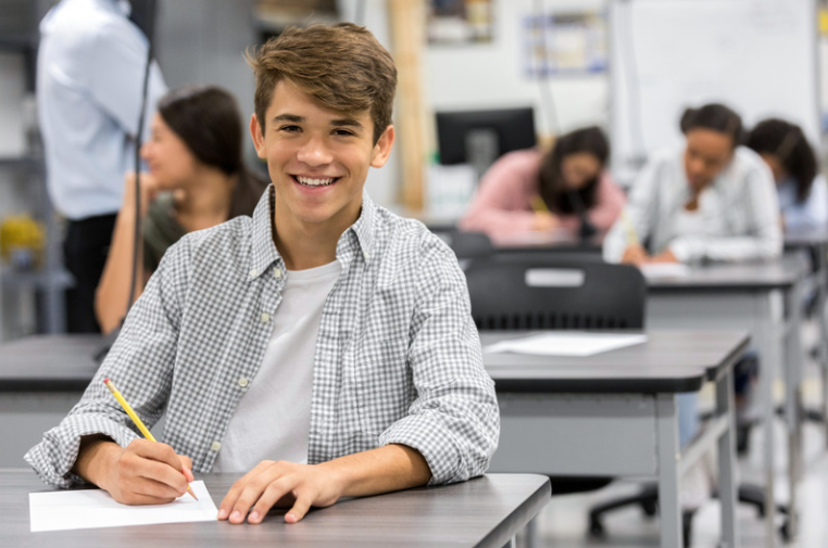 Boy smiling while sitting at a classroom desk