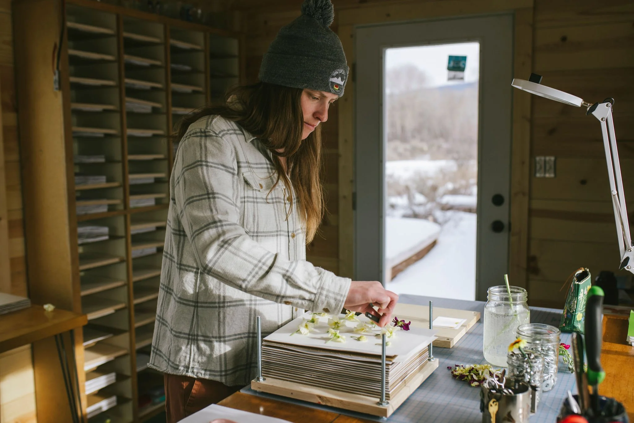 A photograph of the artist pressing stock flowers in her studio.