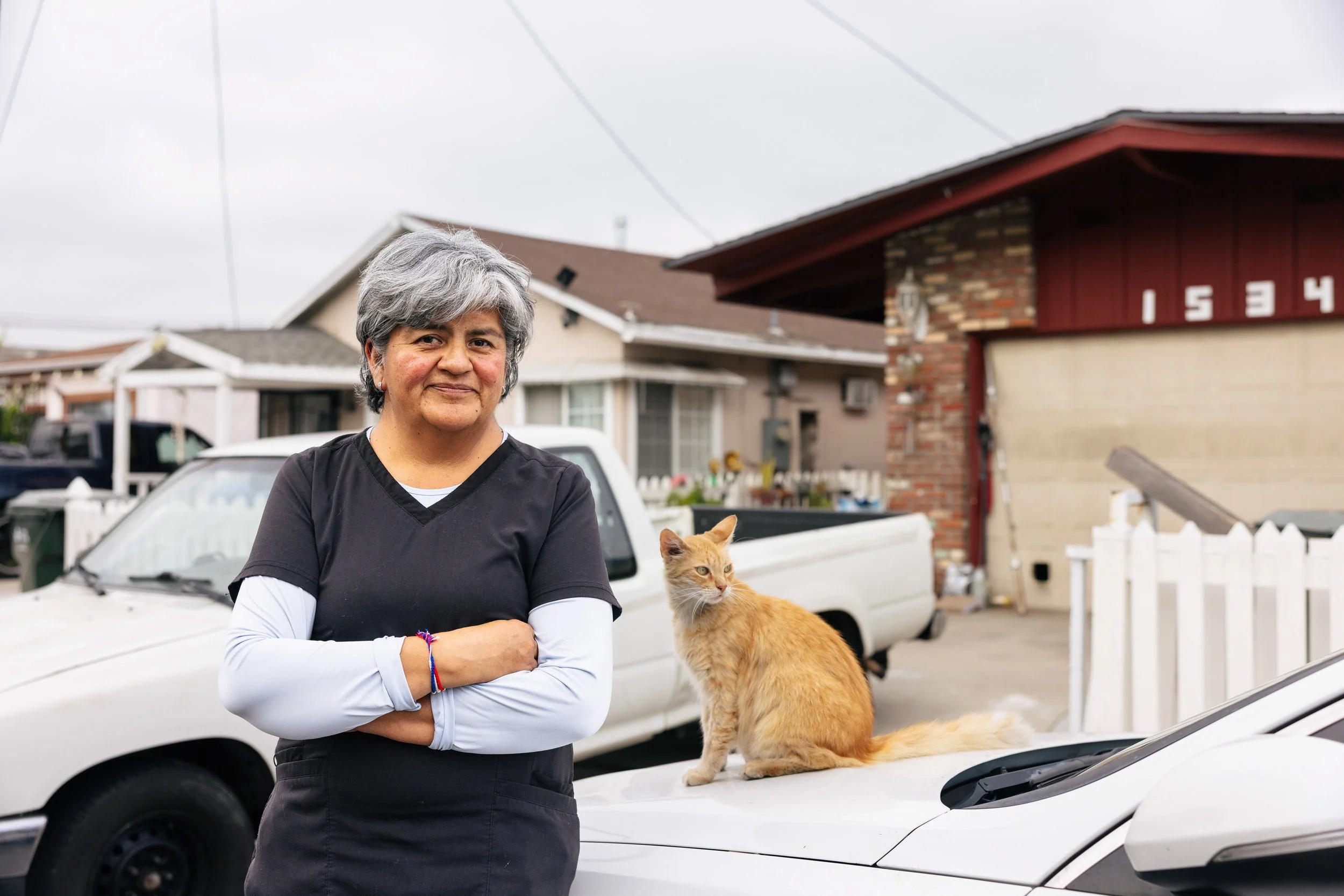A homeowner smiles in front of her home following a GRID Alternatives residential solar installation in Los Angeles, California.