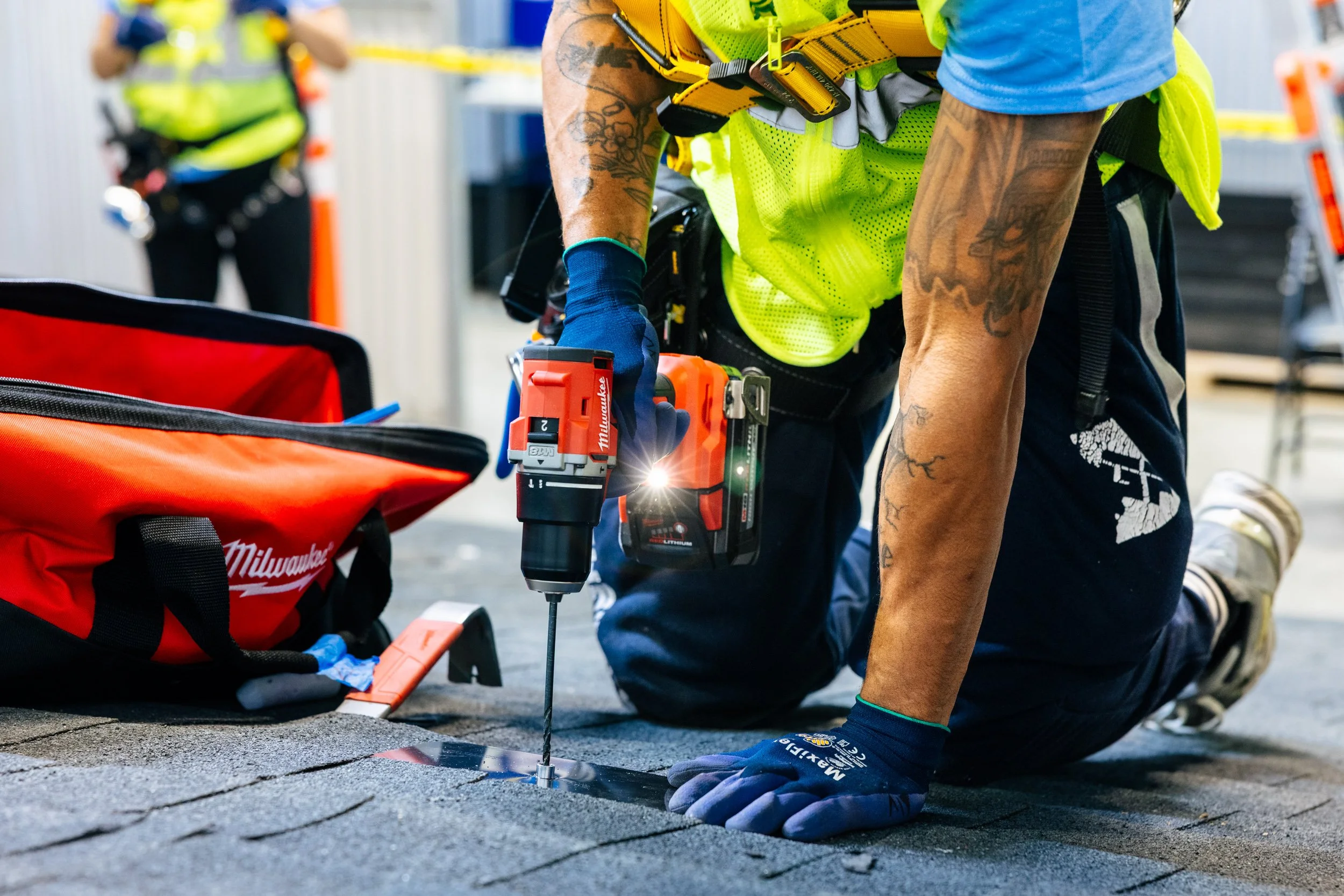 A GRID Alternatives IBT 200 trainee drills solar panel railing during a rooftop installation skills exercise in Los Angeles, California.