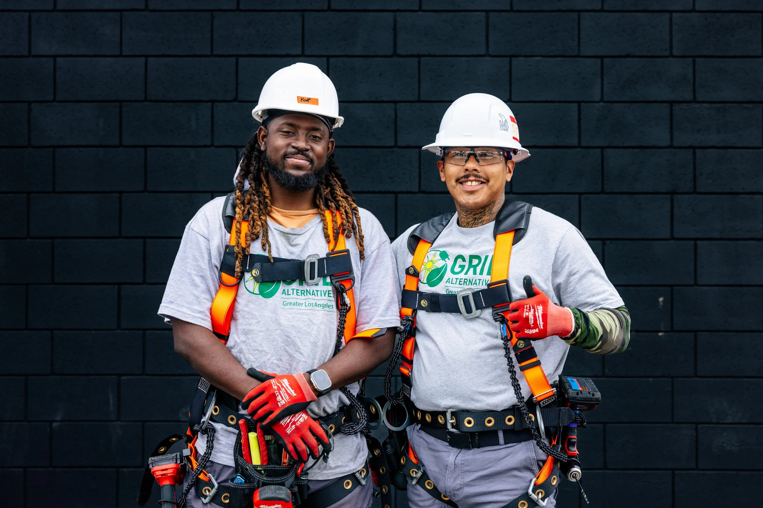 Two GRID Alternatives IBT 200 solar installation trainees pose in full harness gear in Los Angeles, California.