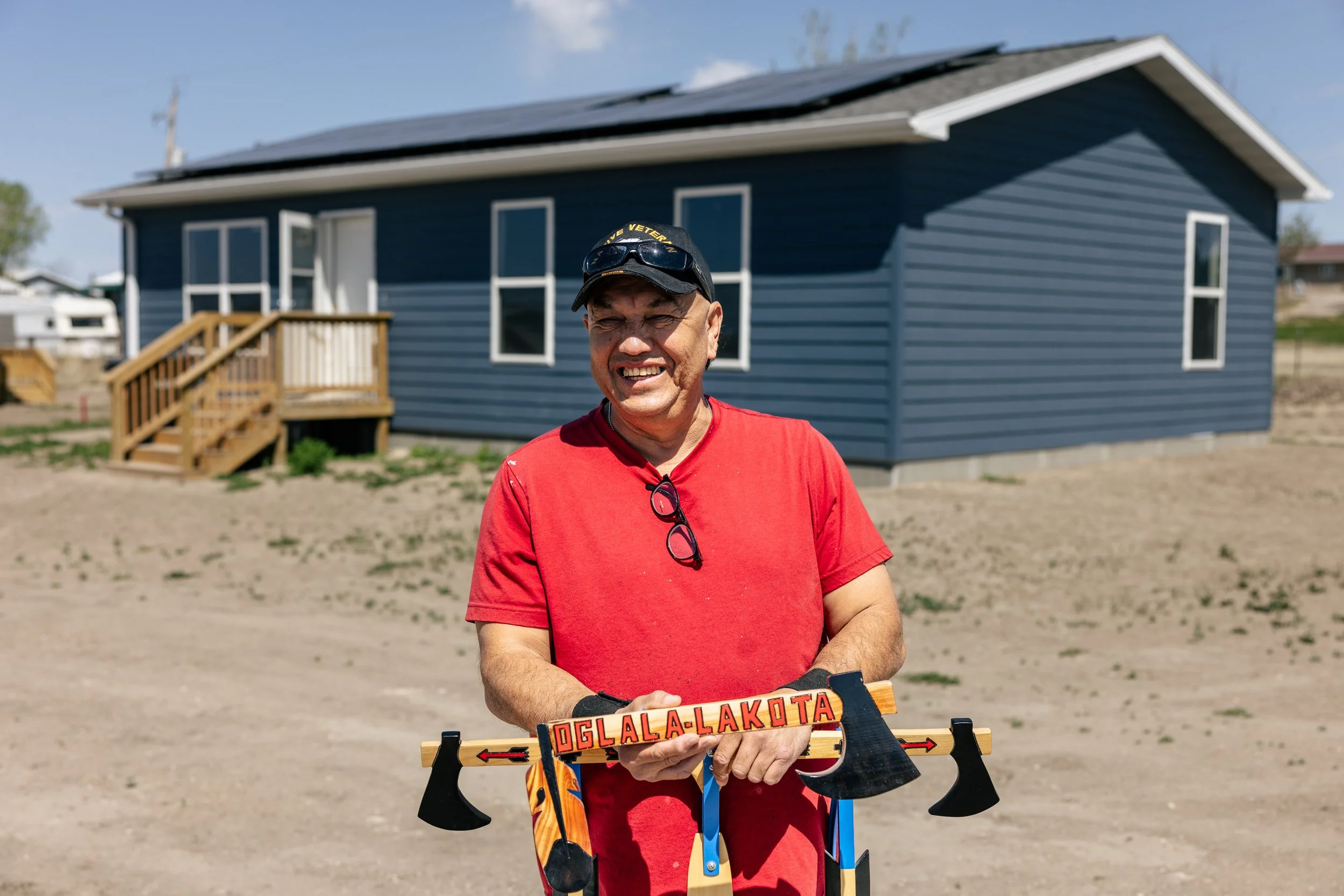 An Oglala Lakota homeowner smiles in front of his home on the Pine Ridge Indian Reservation after a GRID Alternatives Tribal Energy Alternatives solar installation, South Dakota.