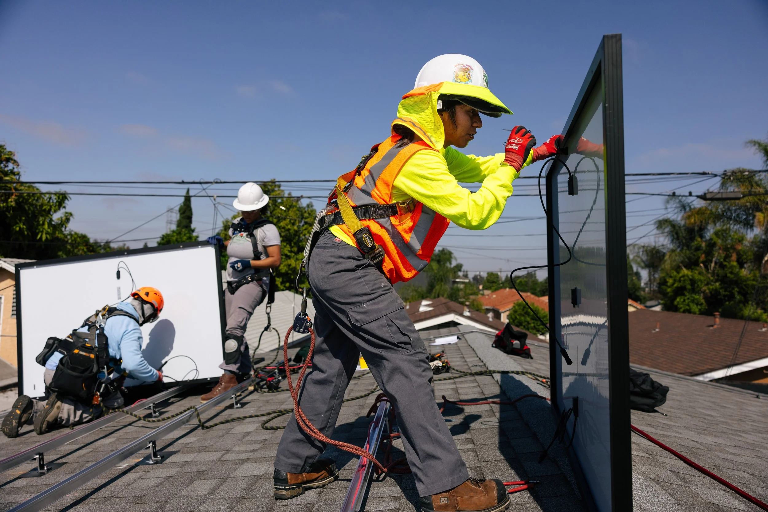 A GRID Alternatives installer guides a solar panel lifted during a residential installation in Los Angeles, California.