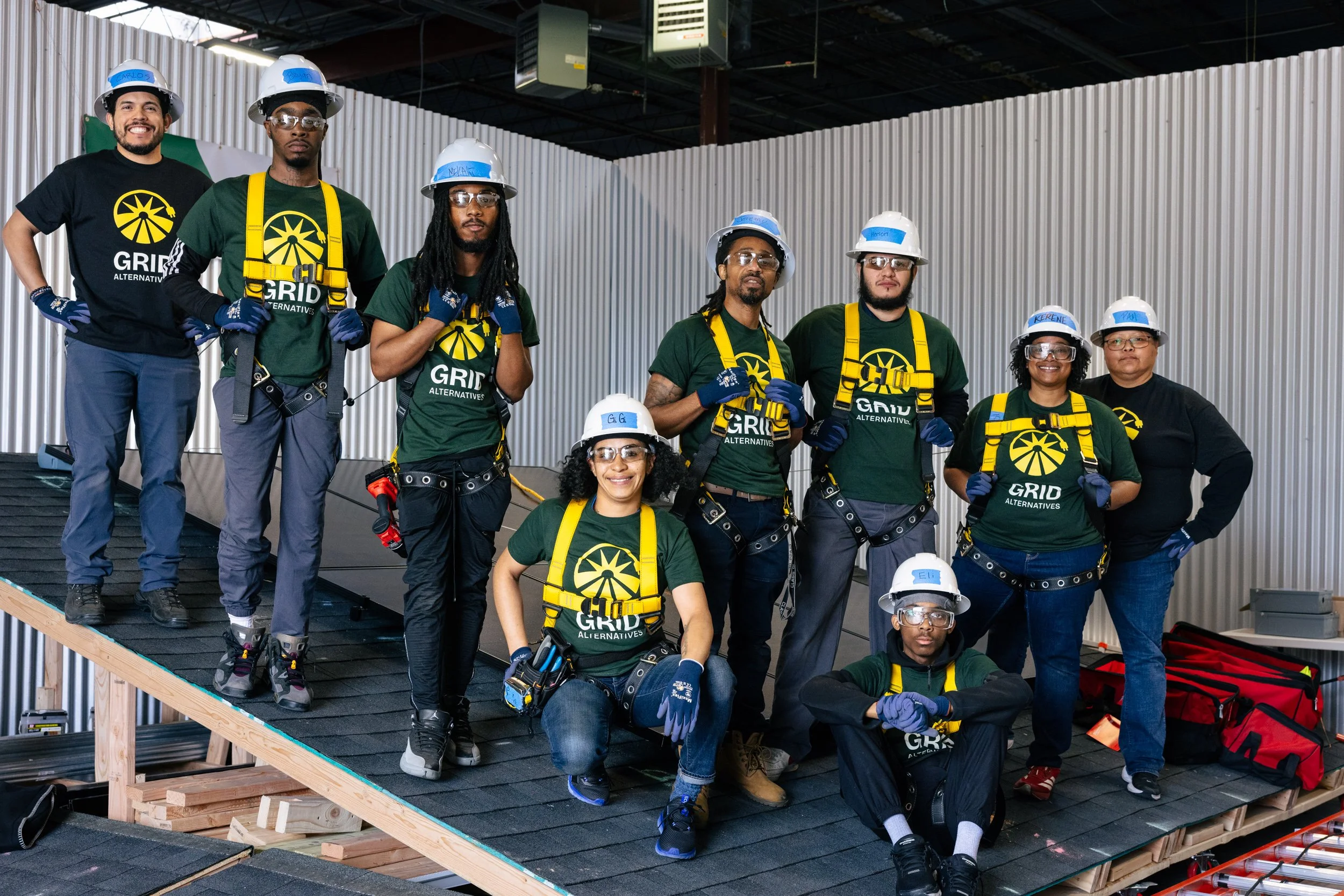 The GRID Alternatives IBT 200 solar installation training cohort poses for a group portrait on a mock rooftop structure at the training facility in Los Angeles, California.
