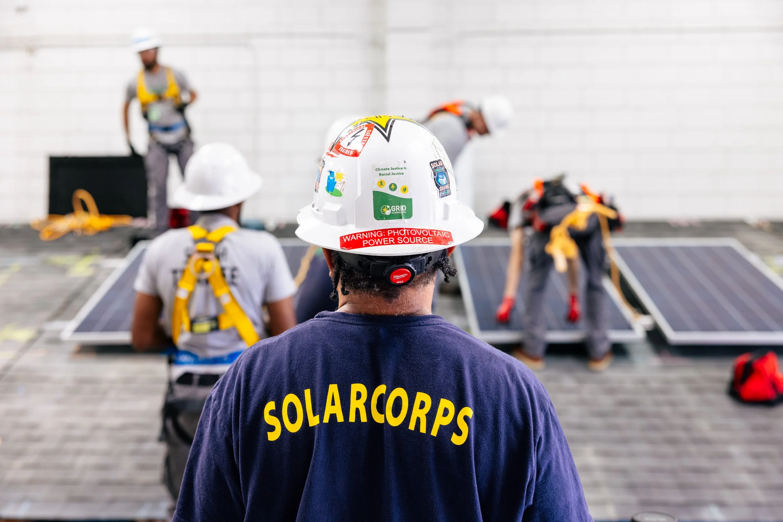 A SolarCorps instructor oversees GRID Alternatives IBT 200 trainees during a rooftop solar installation skills demonstration in Los Angeles, California.