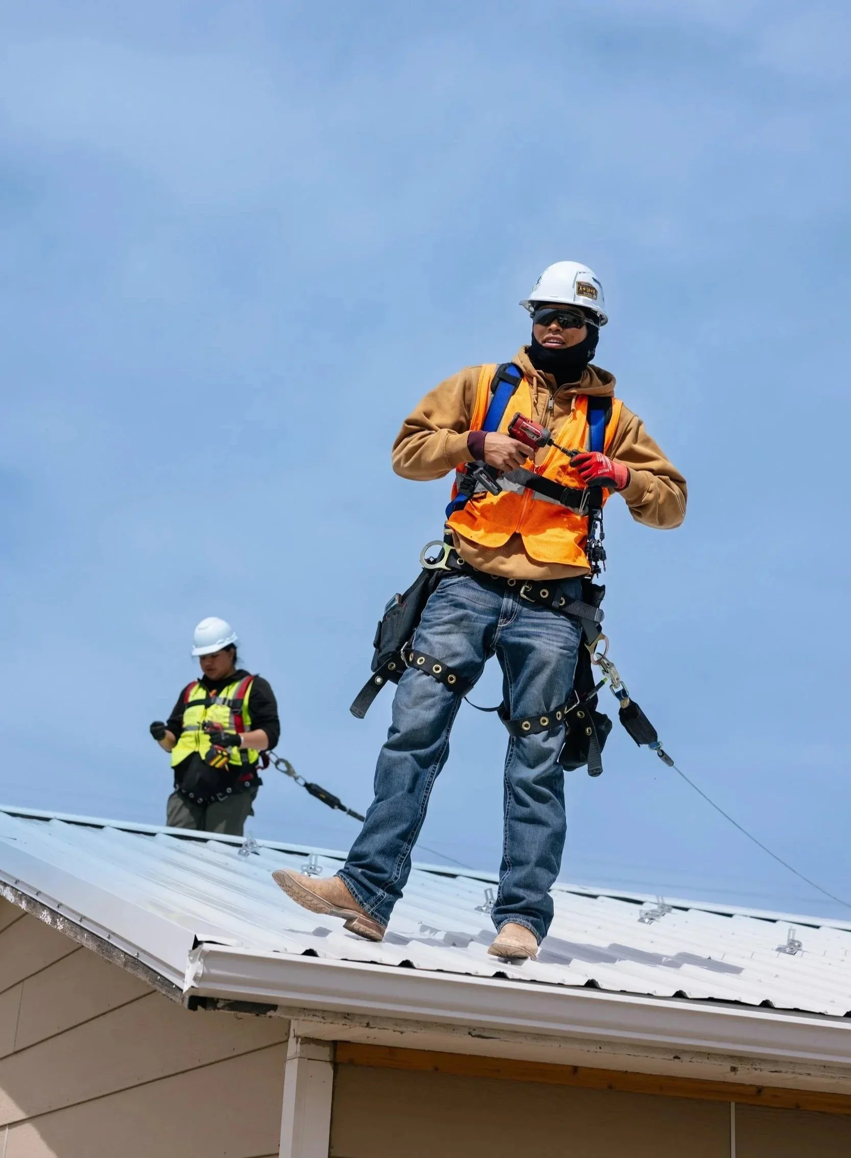 A GRID Alternatives installer stands on a residential rooftop during a solar installation at the Pine Ridge Indian Reservation, South Dakota.