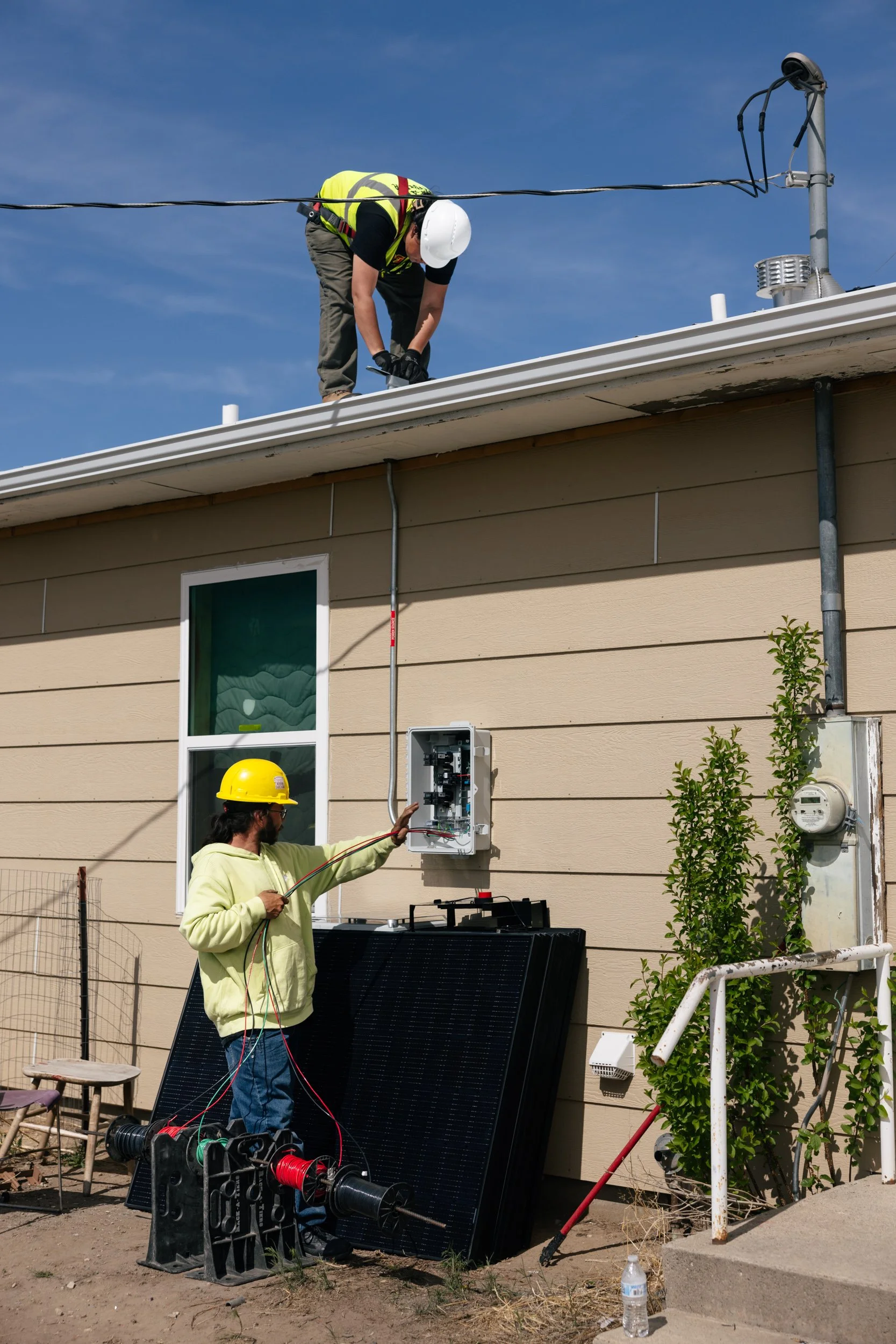 A GRID Alternatives installer works on electrical equipment at a residential solar installation site in Pine Ridge, South Dakota.