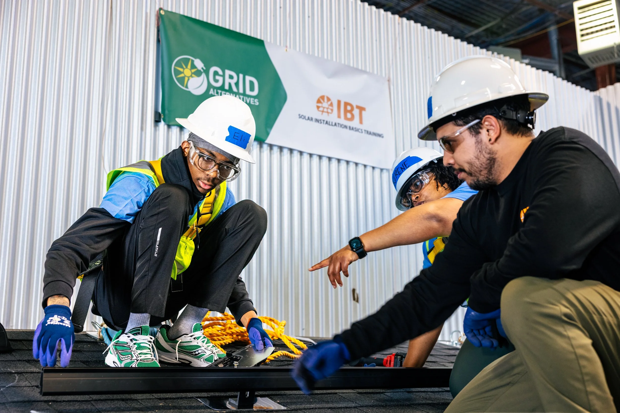 GRID Alternatives IBT 200 trainees practice solar panel rail installation on a mock rooftop at the training facility in Los Angeles, California.