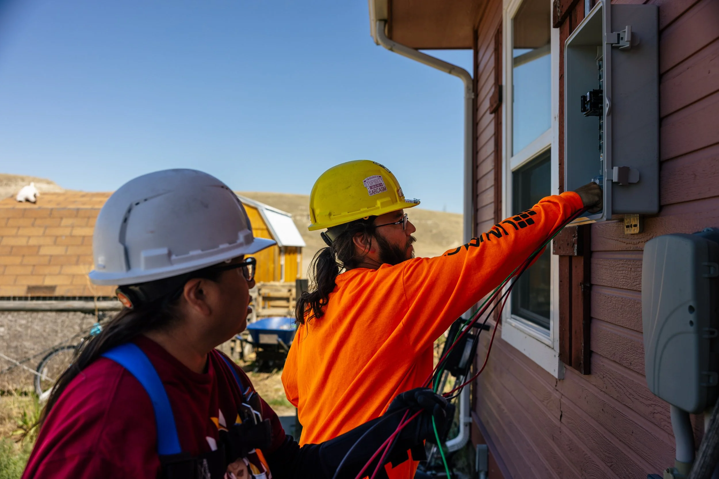 GRID Alternatives installers inspect an electrical panel during a residential solar installation at the Pine Ridge Indian Reservation, South Dakota.