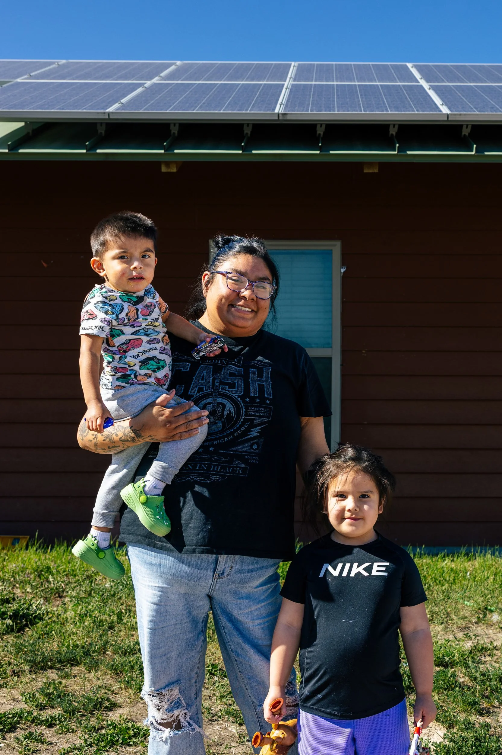 A homeowner and children stand in front of their home on the Pine Ridge Indian Reservation after a GRID Alternatives solar installation, South Dakota.