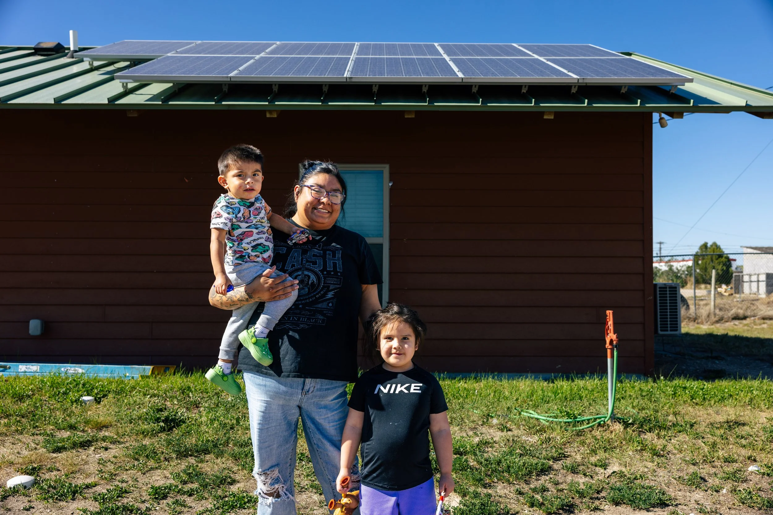 A homeowner and children stand in front of their home on the Pine Ridge Indian Reservation following a GRID Alternatives Tribal Energy Alternatives solar installation, South Dakota.