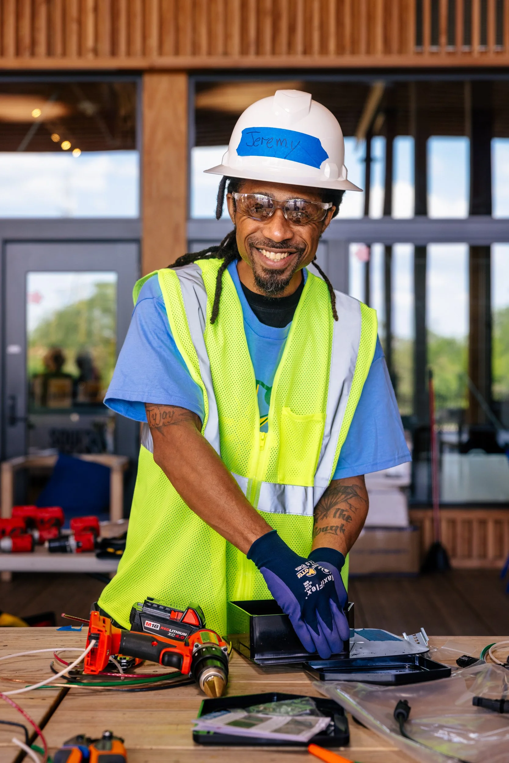 A GRID Alternatives IBT 120 trainee smiles during a hands-on electrical training session at the Sycamore and Oak facility in Washington, D.C.