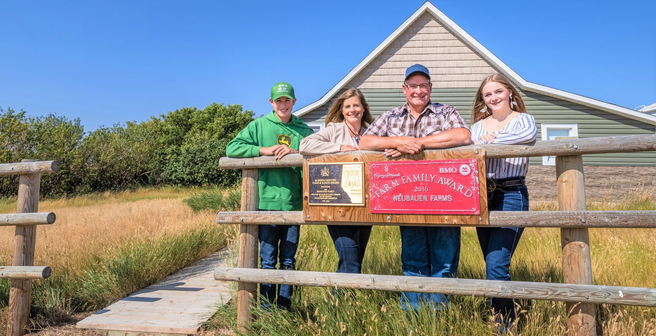 family standing beside farm family sign