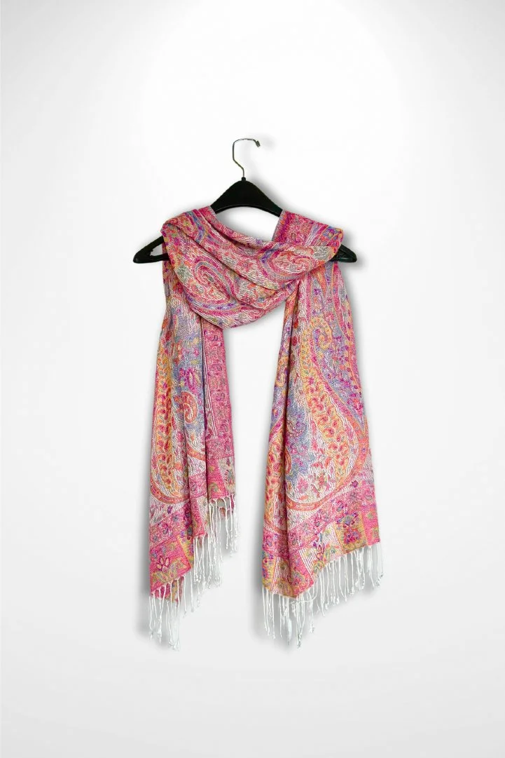 Pink multi-colored pashmina scarf shawl with details of blue, yellow, pink, purple, and orange. Topped with small iridescent rainbow sparkling gems. Fringe color is white.