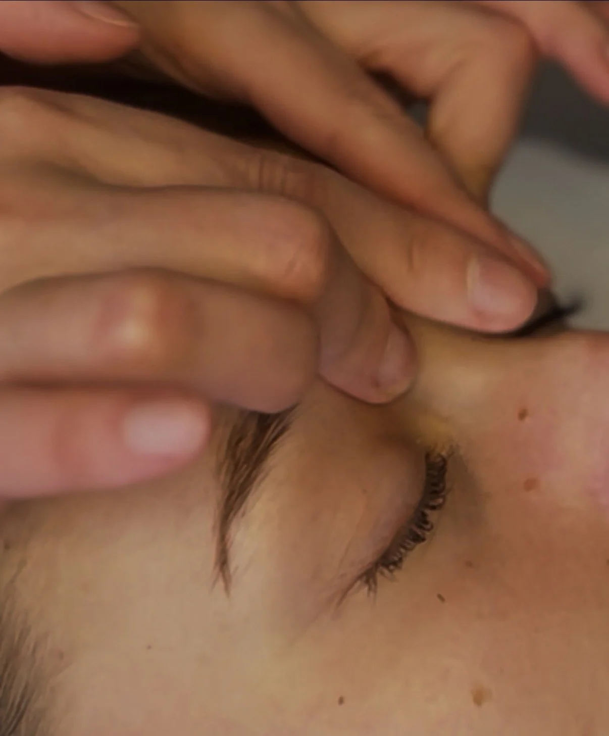 A woman receiving a facial treatment at a spa or skincare clinic, with a skincare professional applying a mask or treatment on her face.