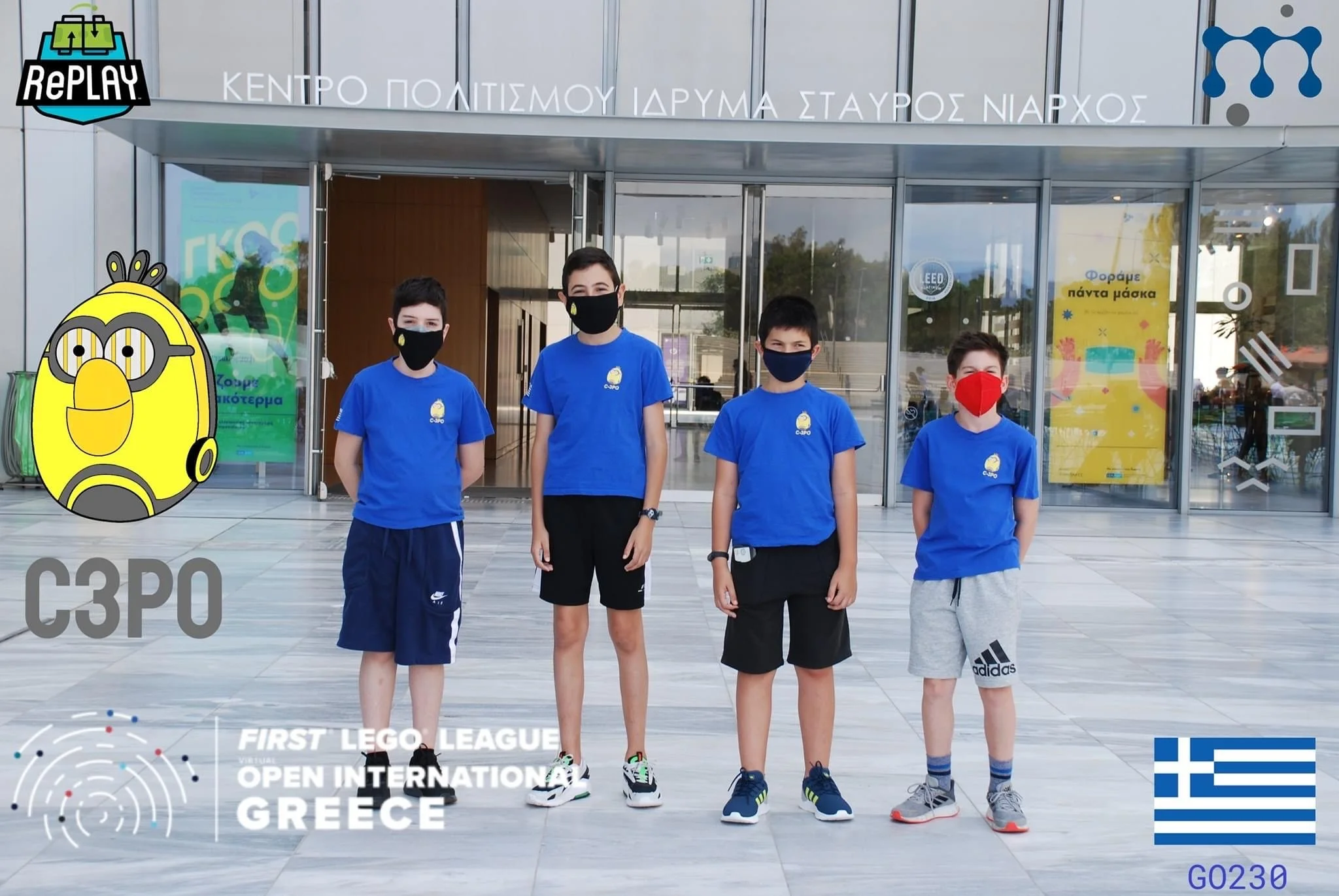 Four children standing in front of a modern building entrance, wearing face masks and blue shirts with a yellow logo, participating in the First LEGO League Greece international robotics competition.