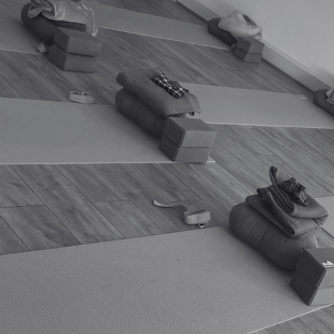 Yoga mats and pillows arranged on blocks in a studio with wooden floors, ready for a yoga class.