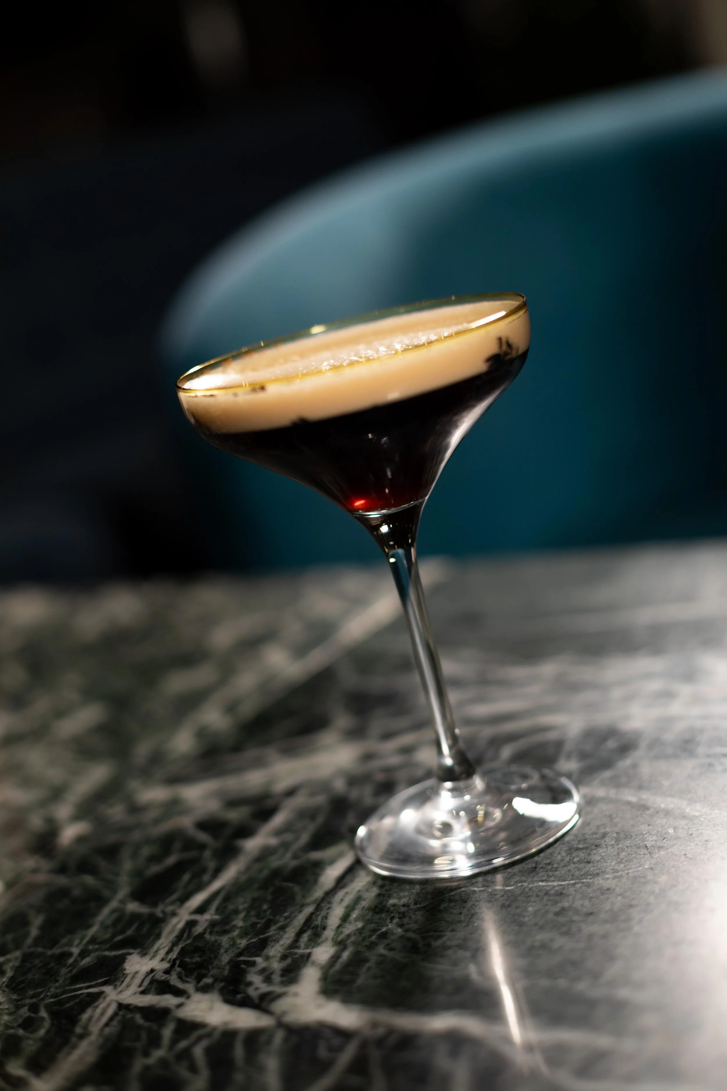 En cocktail i ett coupeglas på en mörk marmorbord.