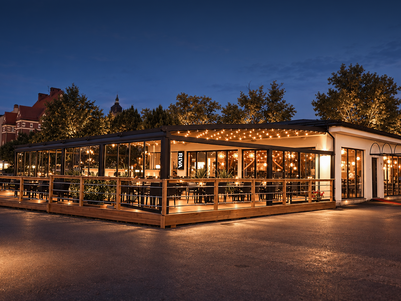 Utsidan av en mysig restaurang med mycket belysning och stora glasfönster, kvällstid.