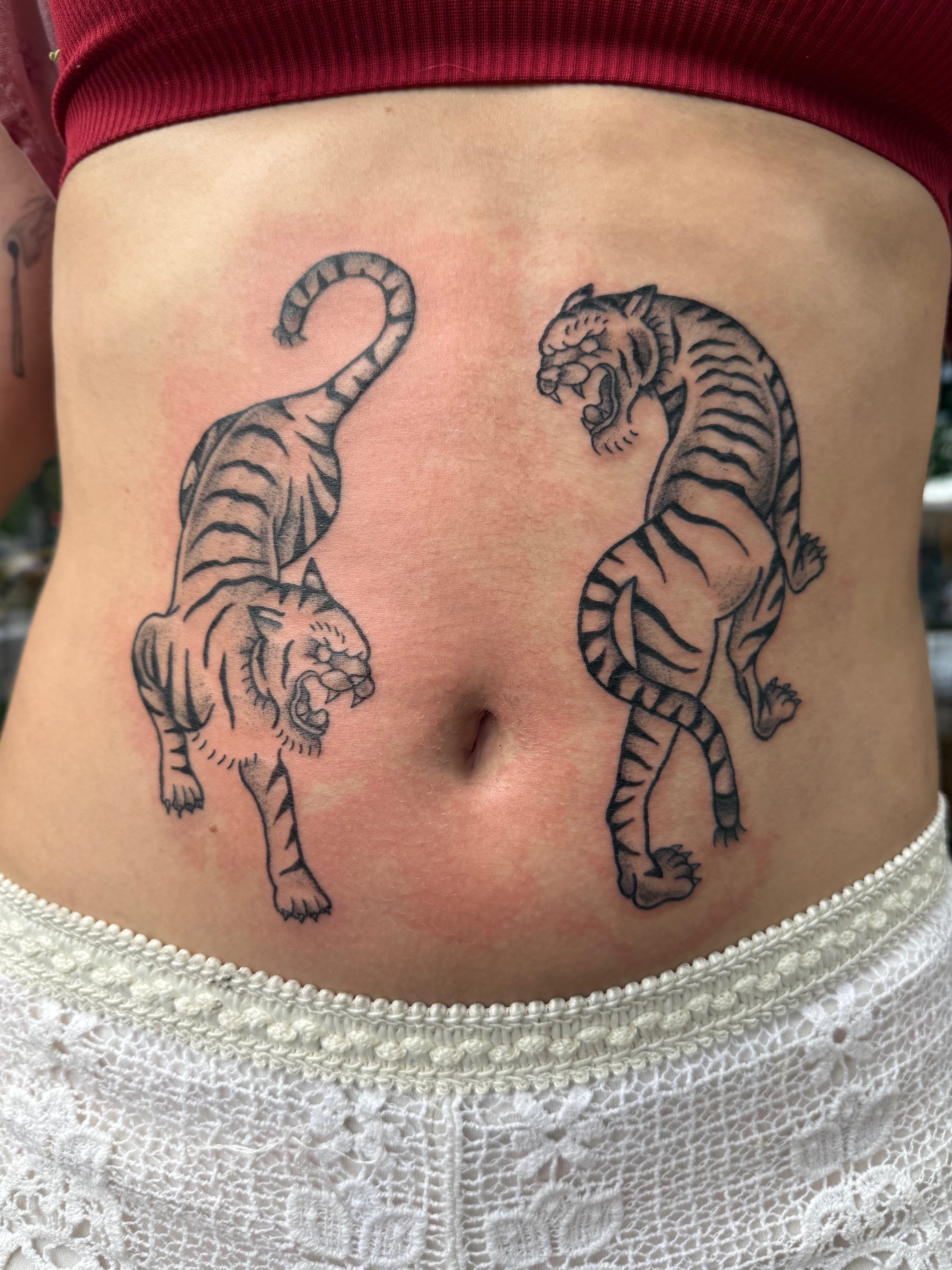 Traditional tattoo of two tigers on the stomach in black and gray ink by Leah Fries, located at Moth to a Flame Tattoo, Old Colorado City