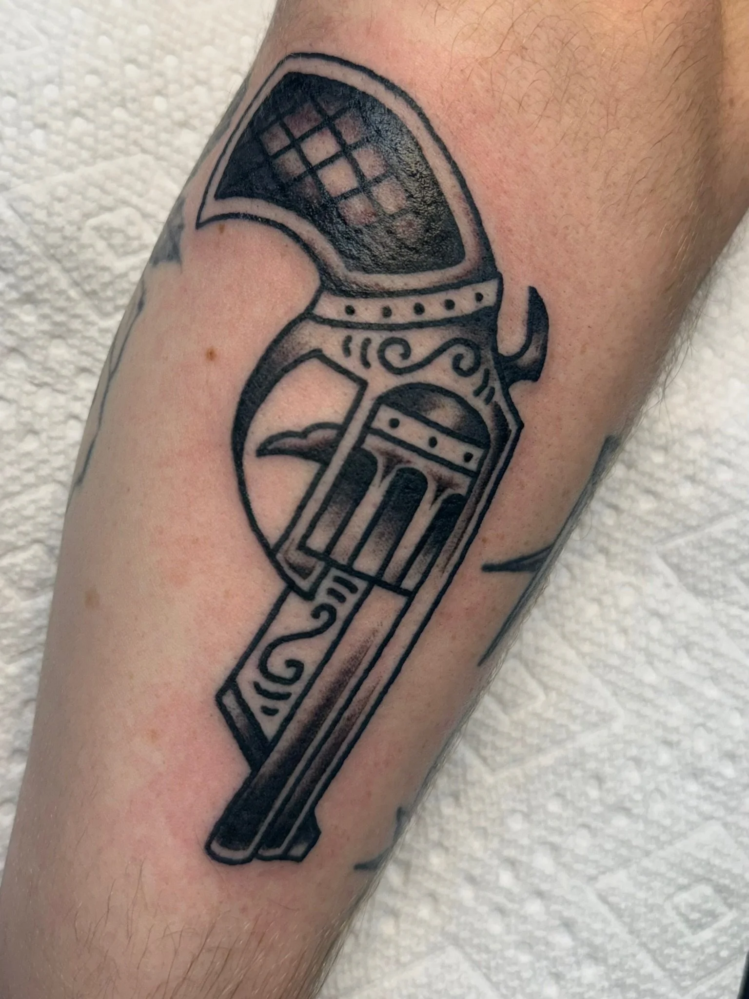 Traditional tattoo of a pistol in black and gray ink by Leah Fries, located at Moth to a Flame Tattoo, Colorado Springs