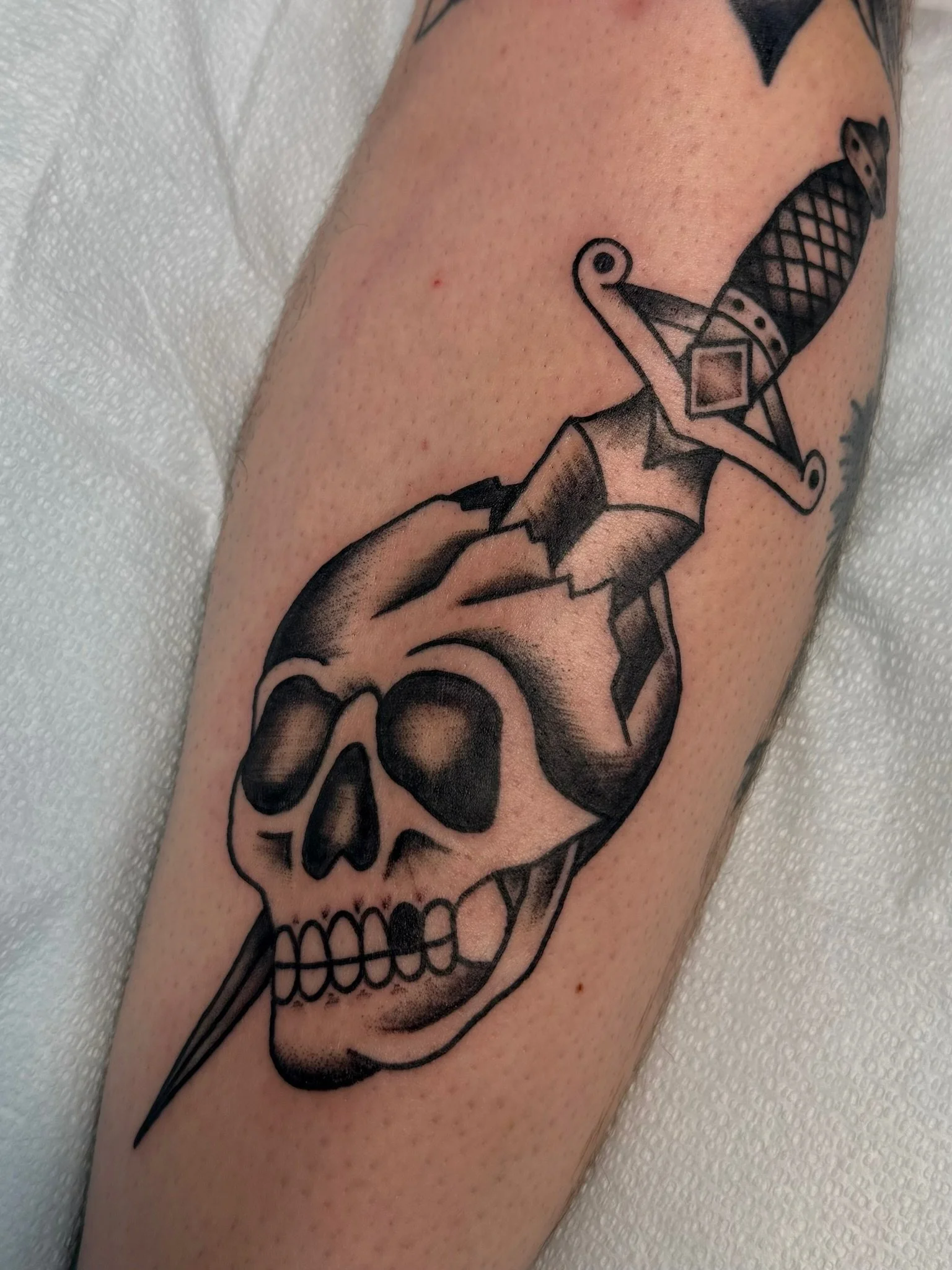Traditional tattoo of a dagger and skull in black and gray ink by Leah Fries, located at Moth to a Flame Tattoo, Old Colorado City