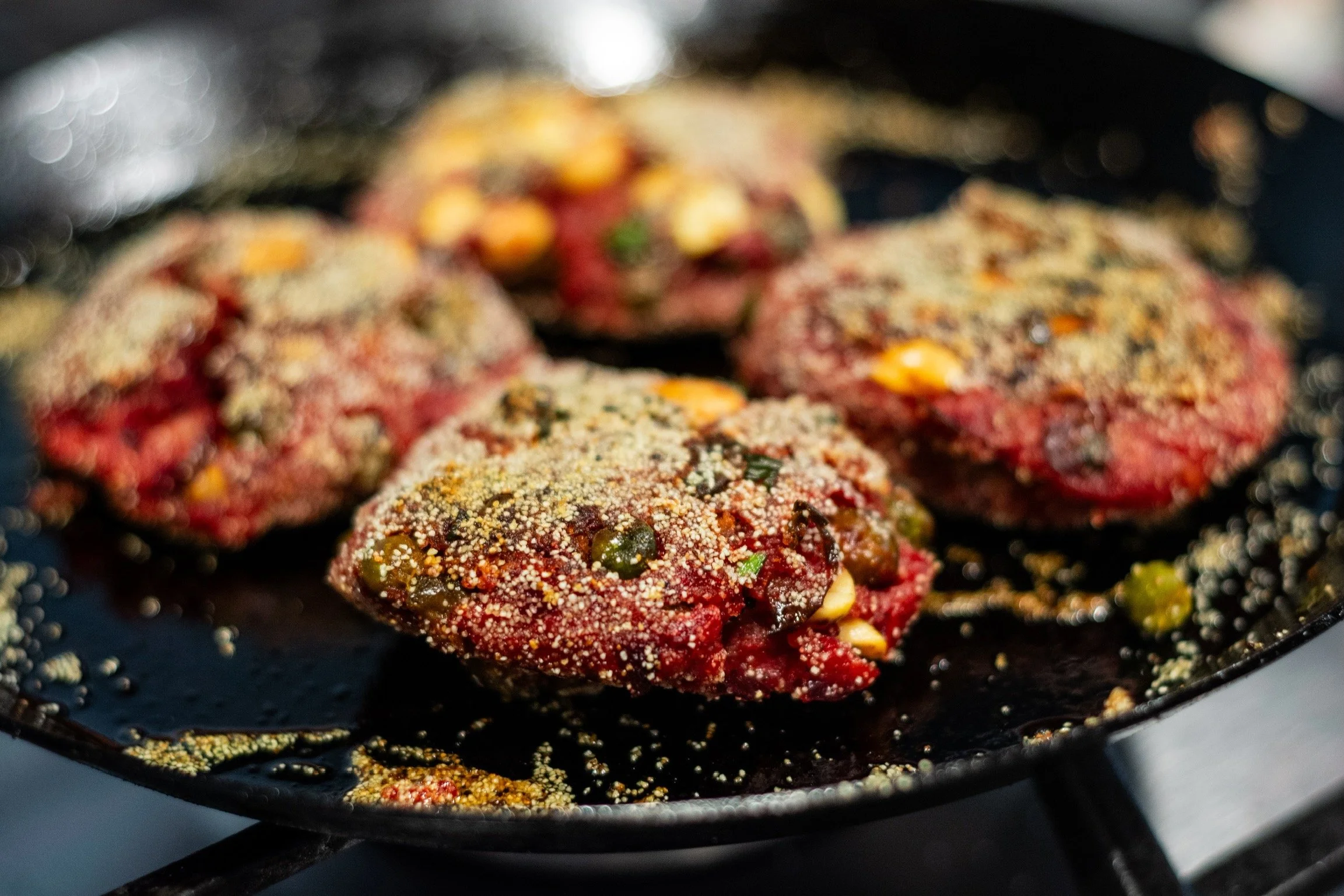 Hamburguesas de carne en una sartén con condimentos y especias antes de cocinarse.