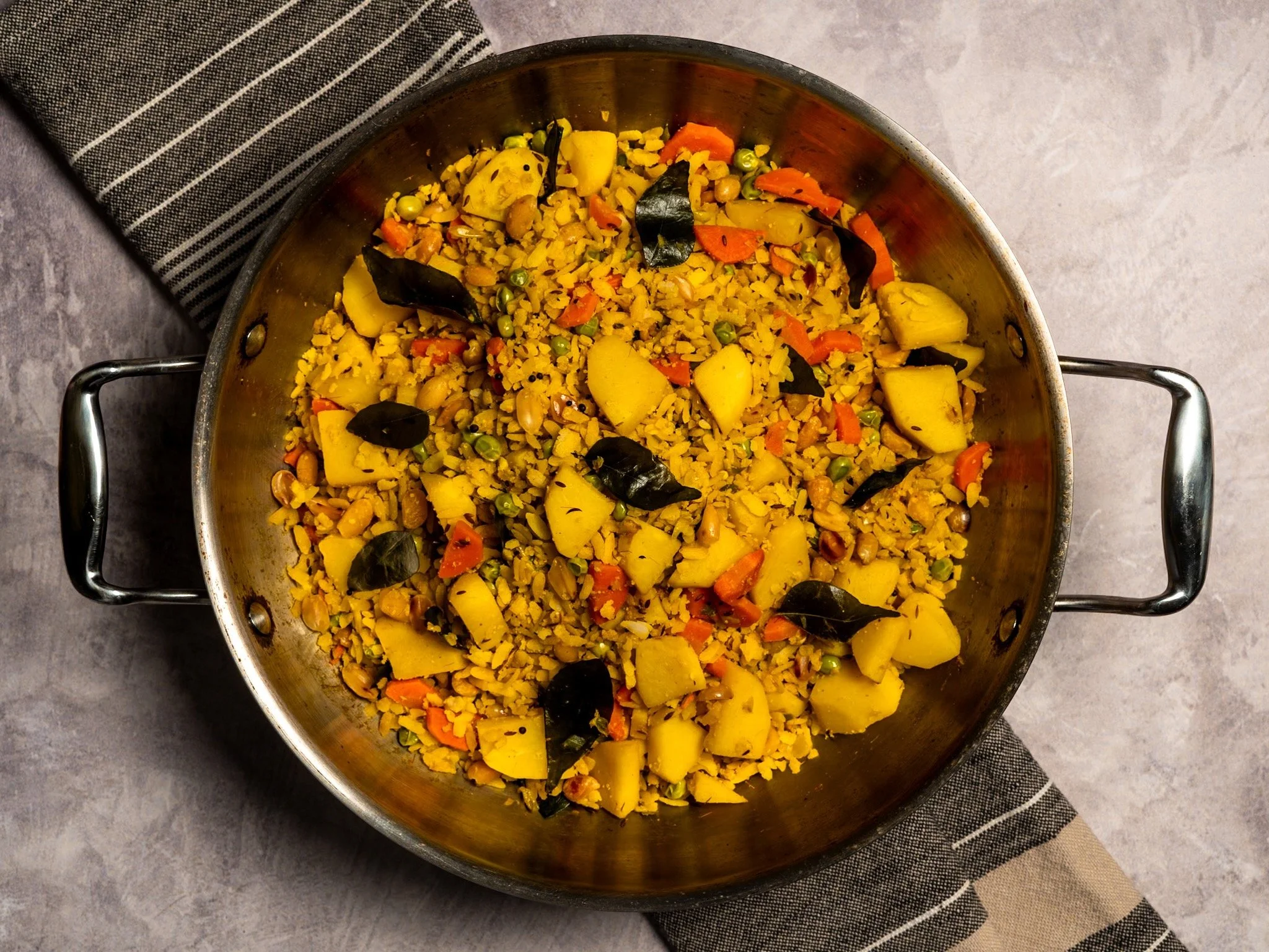 Plato de arroz con verduras y hojas de laurel en una sartén de acero inoxidable.