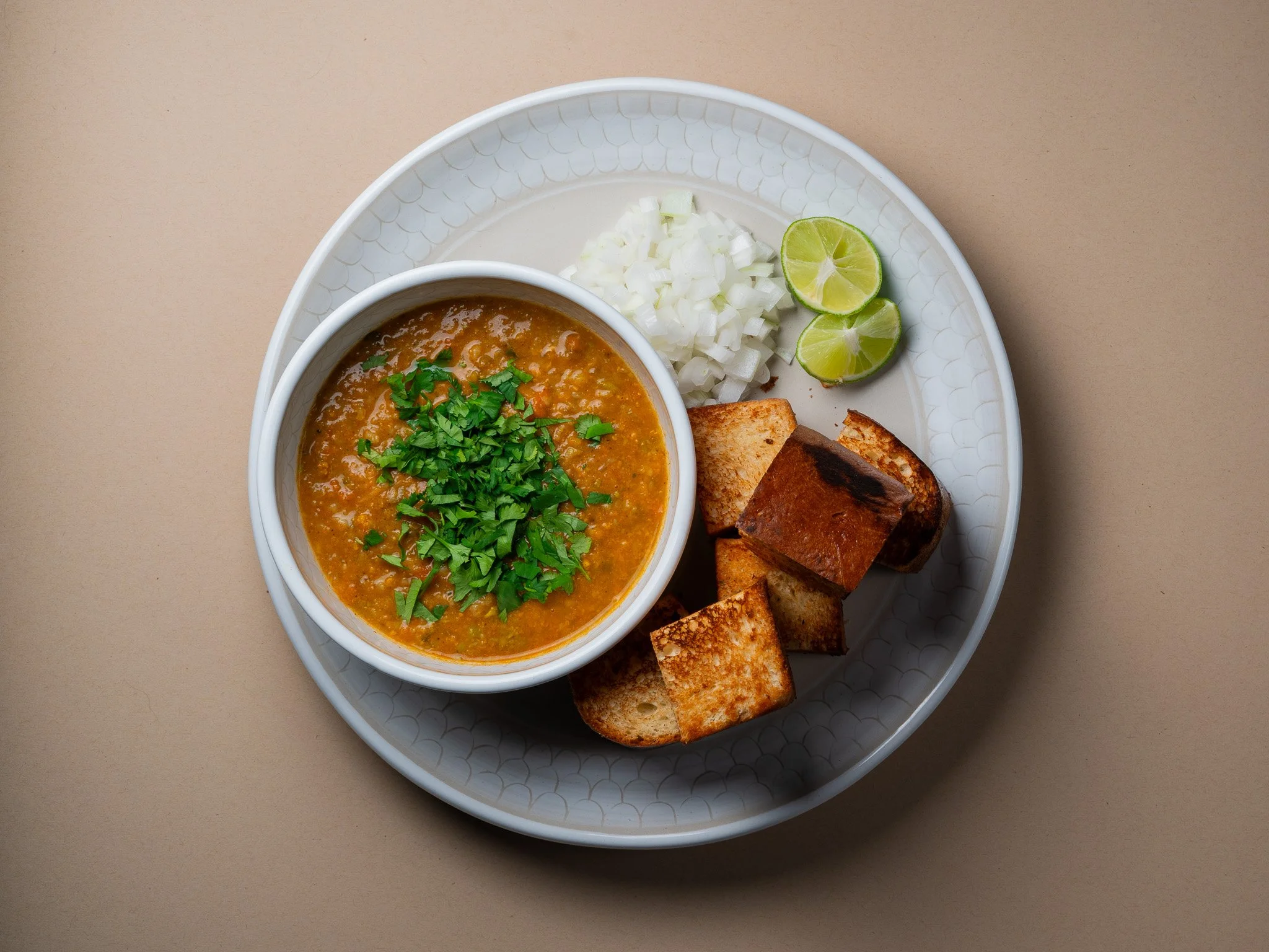 Plato mexicano con sopa de frijoles, totopos, cebolla picada, y limones.